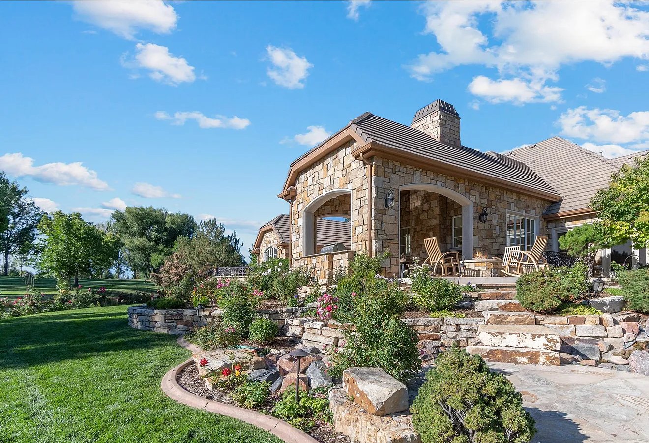 Stone home with a covered patio, terraced gardens, and a lawn
