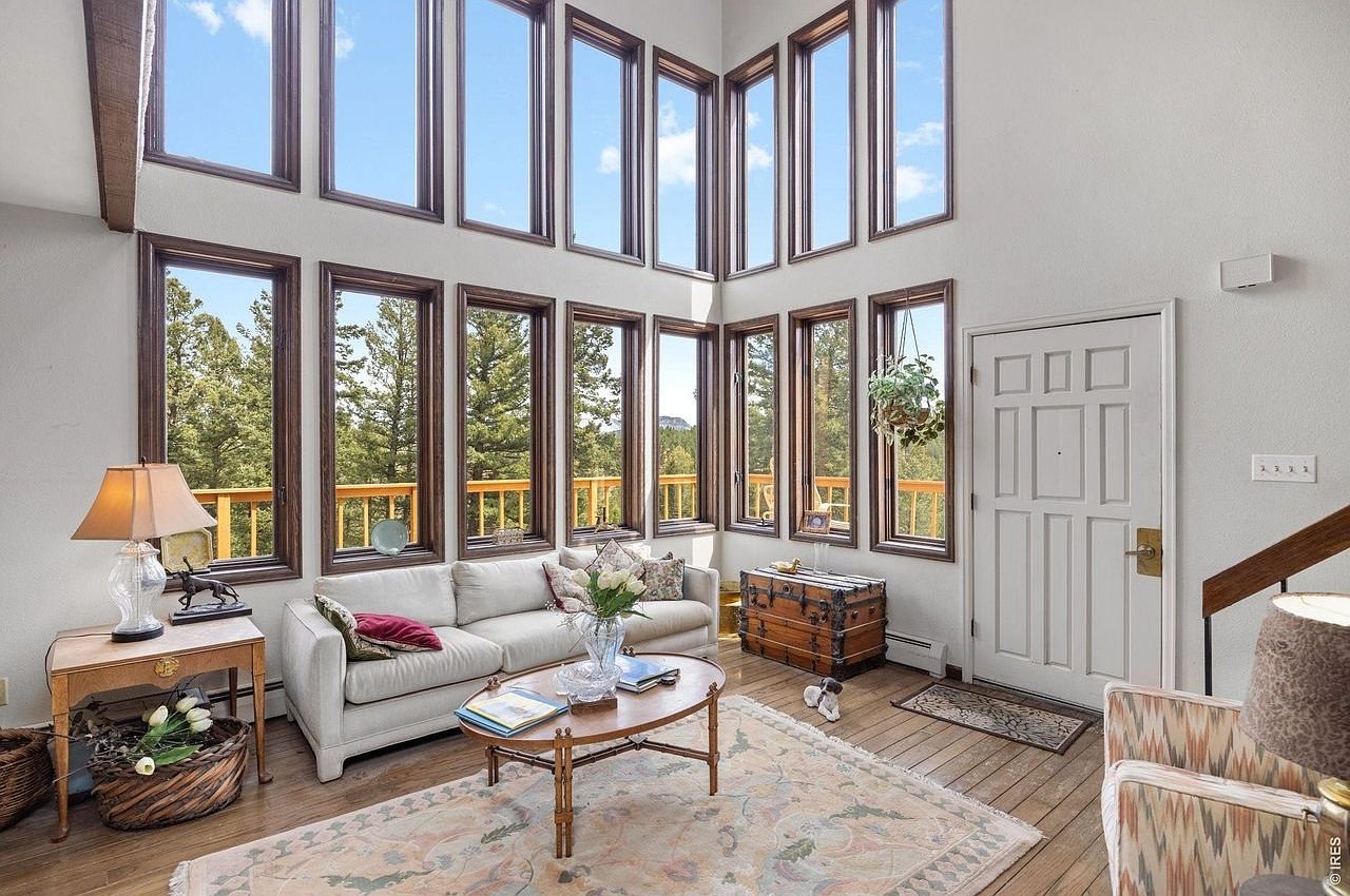 Two-story wall of windows looking out to pines in a mountain great room