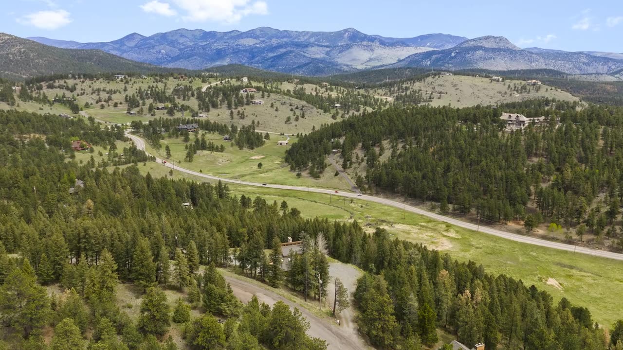 Drone view over a forested valley near Evergreen with peaks behind